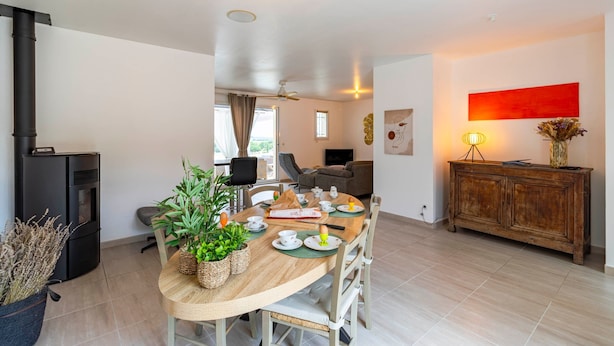 A modern living space with a dining area, a black stove, and a red abstract painting. - L’Horizon de Ribérac - Piscine privée chauffée (Saint-Martin-de-Ribérac)