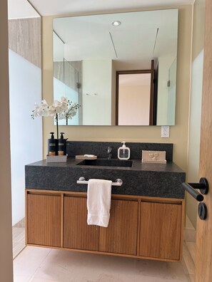 A modern bathroom with a granite countertop, a large mirror, a sink, and a towel rack. - Loft 10 minutes from the beach, 2 queen-size beds, kitchenette, Wi-Fi, gym, Nuevo Vallarta (Flamingos)