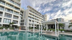 A modern hotel with a swimming pool, multiple balconies, and a covered outdoor seating area. - Loft 10 minutes from the beach, 2 queen-size beds, kitchenette, Wi-Fi, gym, Nuevo Vallarta (Flamingos)