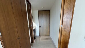 A hallway with wooden doors and a tiled floor, leading to a room with a white door. - Loft 10 minutes from the beach, 2 queen-size beds, kitchenette, Wi-Fi, gym, Nuevo Vallarta (Flamingos)