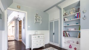 A room with a white dresser, a bookshelf, a door, and a patterned rug. - La Maison Maudanaur - Maison familiale avec jardin (Morainville-Jouveaux)