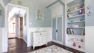 A room with a white dresser, a bookshelf, a door, and a patterned rug.