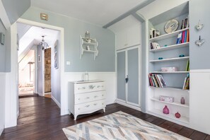 A room with a white dresser, a bookshelf, a door, and a patterned rug. - La Maison Maudanaur - Maison familiale avec jardin (Morainville-Jouveaux)