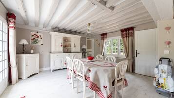 Un comedor con una mesa dispuesta para cuatro, sillas blancas y mantel a cuadros rojo y blanco.