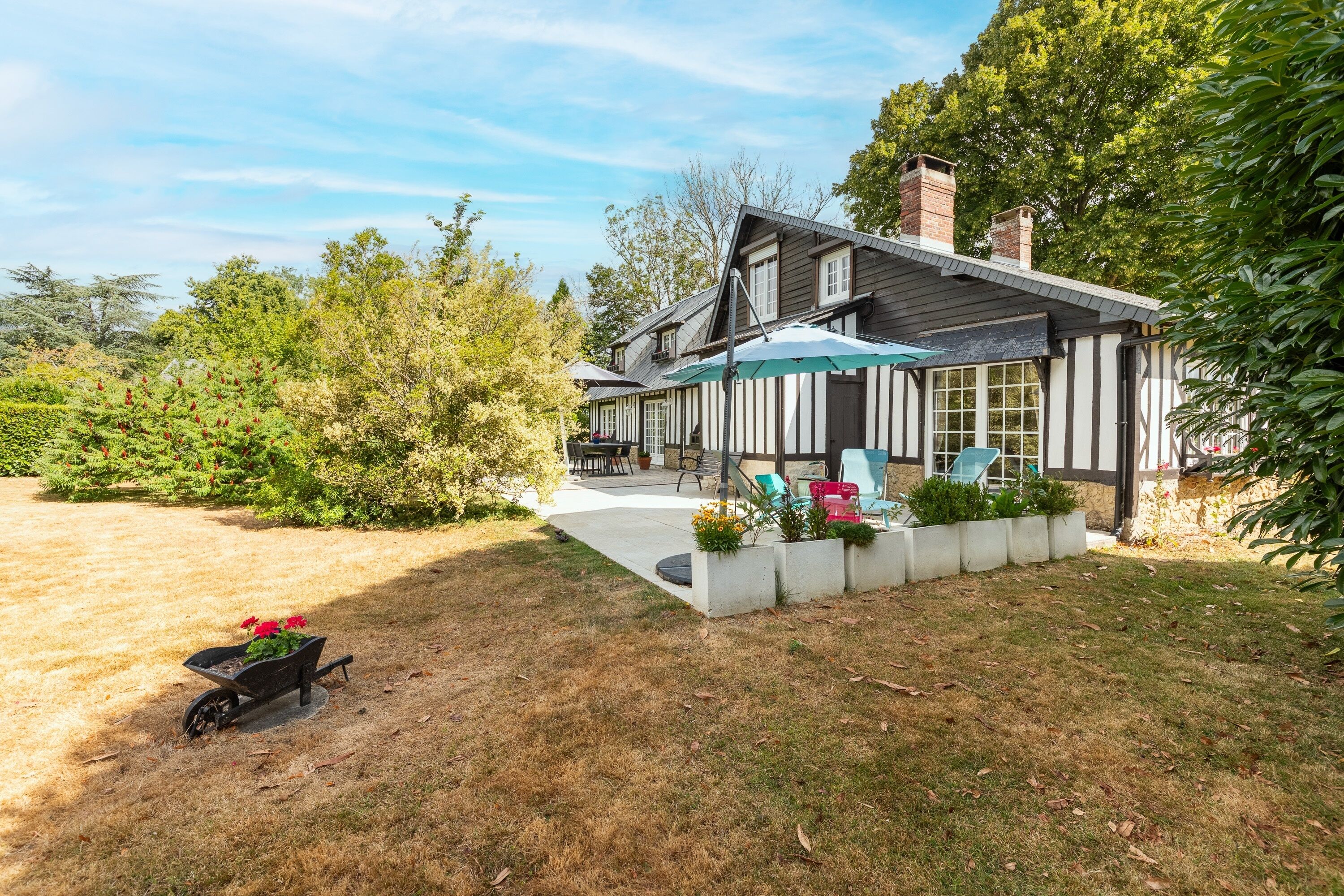 A two-story house with a patio area, outdoor furniture, and a garden.