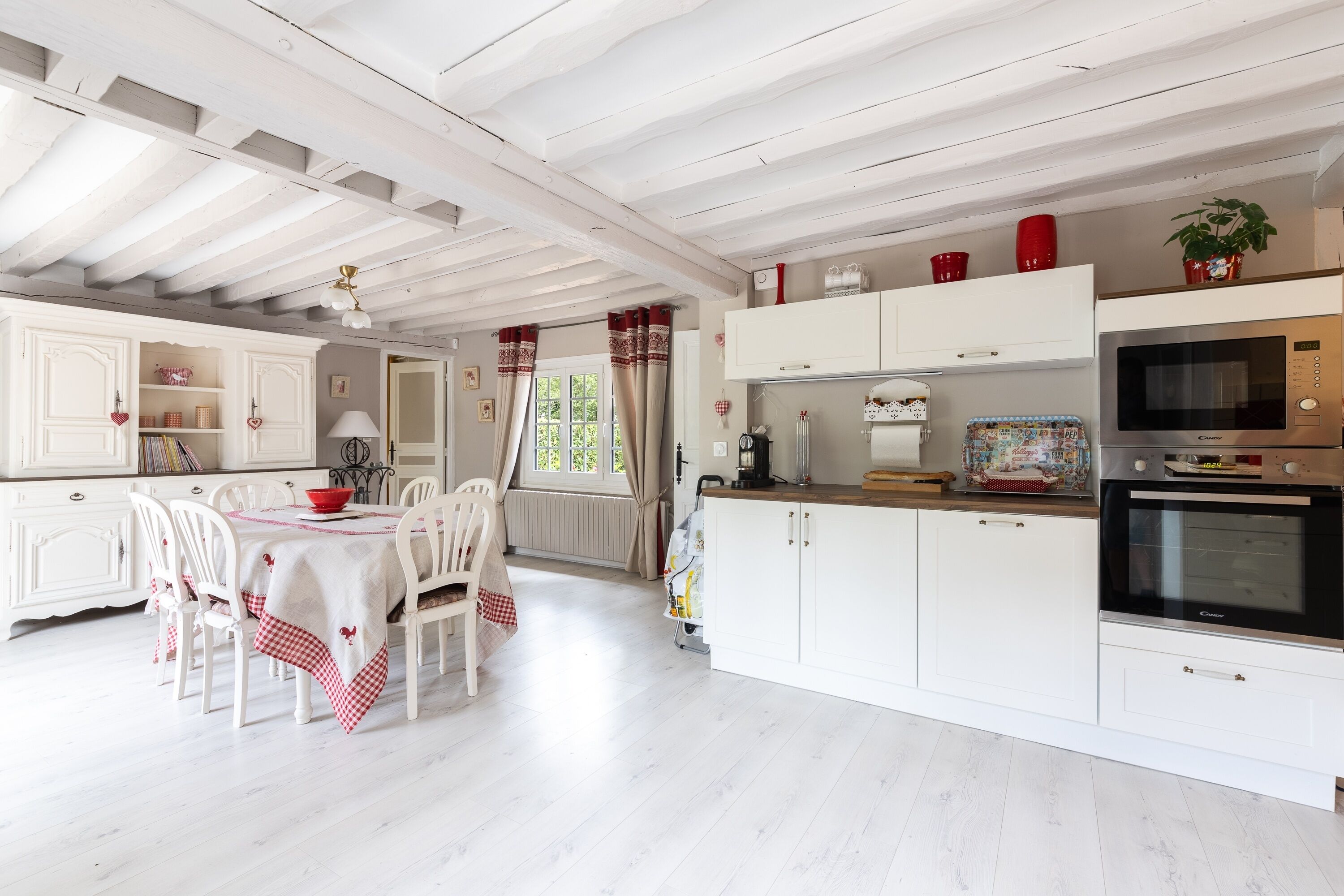 A kitchen with white cabinetry, a dining table with chairs, and a microwave oven.