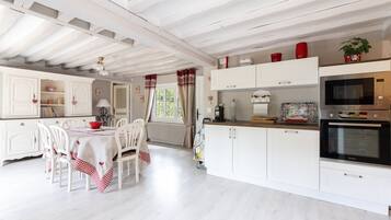 A kitchen with white cabinetry, a dining table with chairs, and a microwave oven.