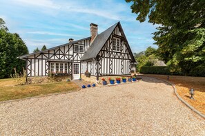 A traditional half-timbered house with a gravel driveway and potted plants. - La Maison Maudanaur - Maison familiale avec jardin (Morainville-Jouveaux)