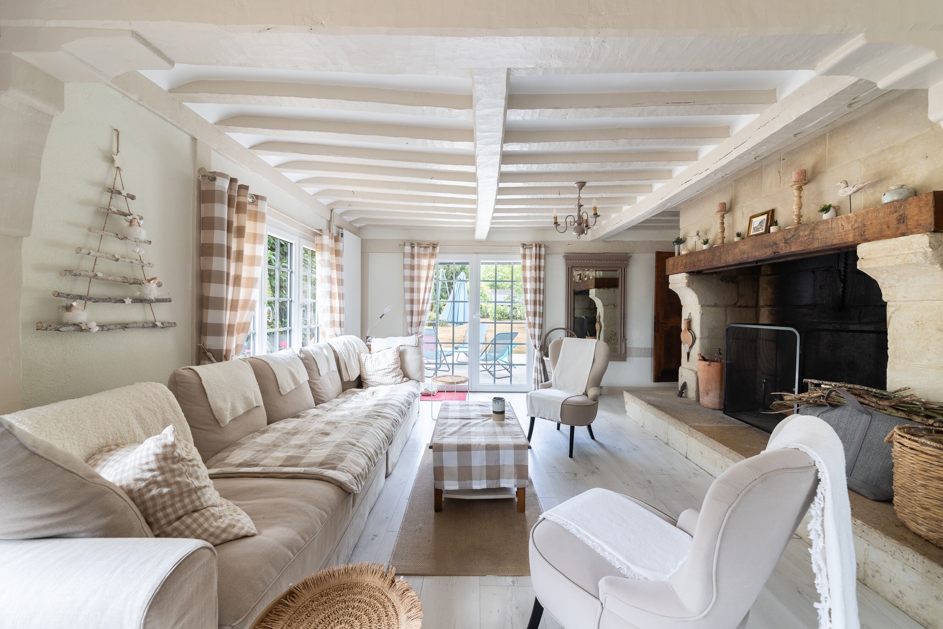A spacious living room with a long sofa, a fireplace, and a view through large windows.