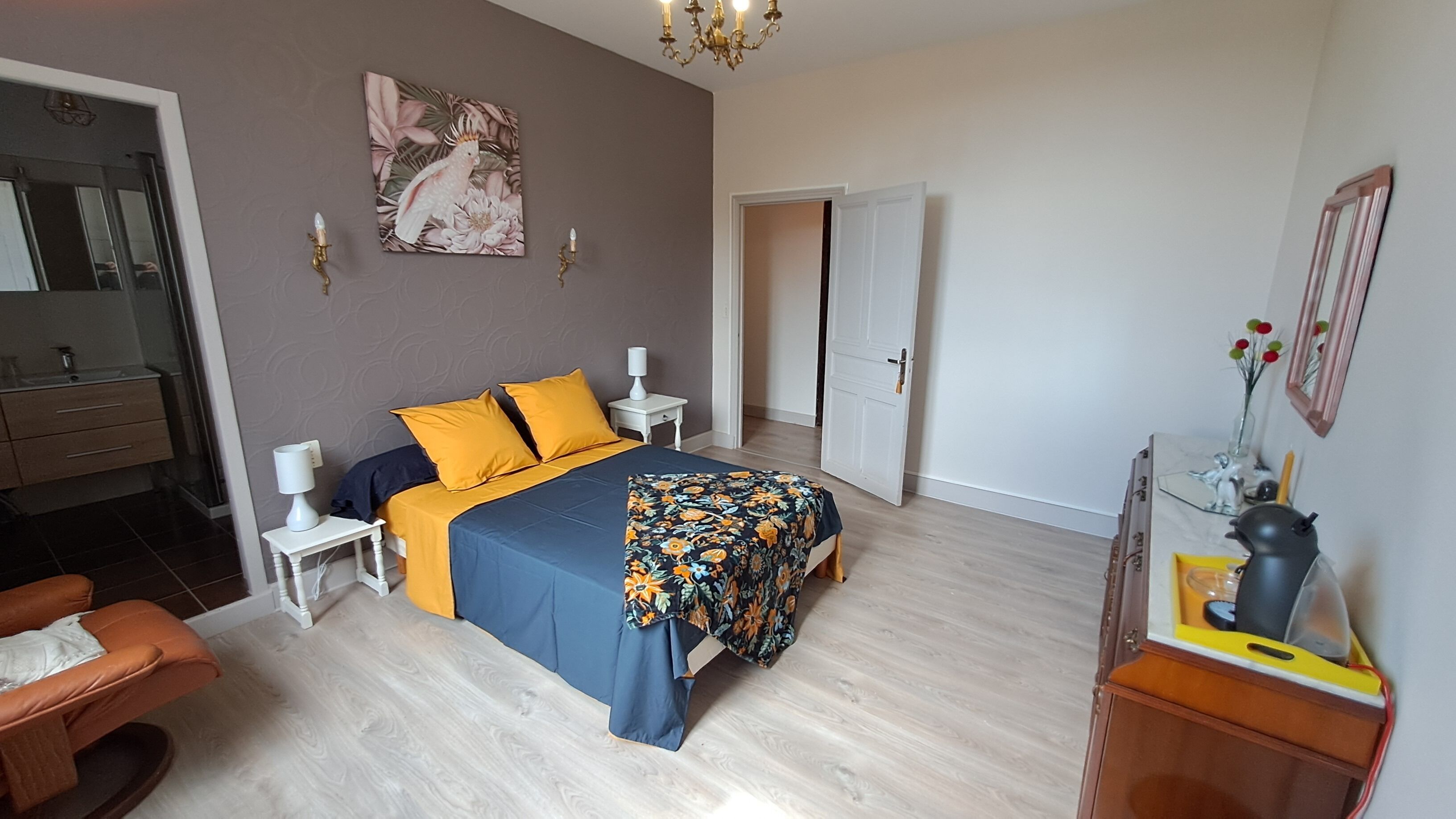 Un dormitorio con una cama, mesitas de noche, un espejo, cómoda y una silla.