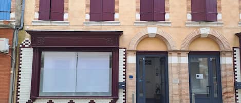 Un edificio con un ventanal grande, una puerta y una pequeña entrada.