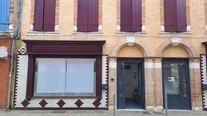 A building with a large window, a door, and a small entrance. - The 3-Star "Gîte de la Halle" (Beaumont-de-Lomagne)