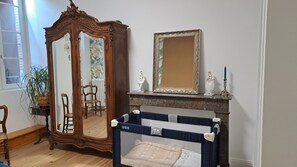 Une pièce comprenant une armoire en bois, un miroir, un tableau encadré, une commode et une barrière de sécurité pour bébé.