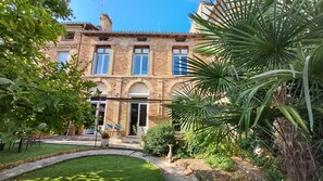 Un bâtiment en briques de deux étages, avec un jardin à l’avant.