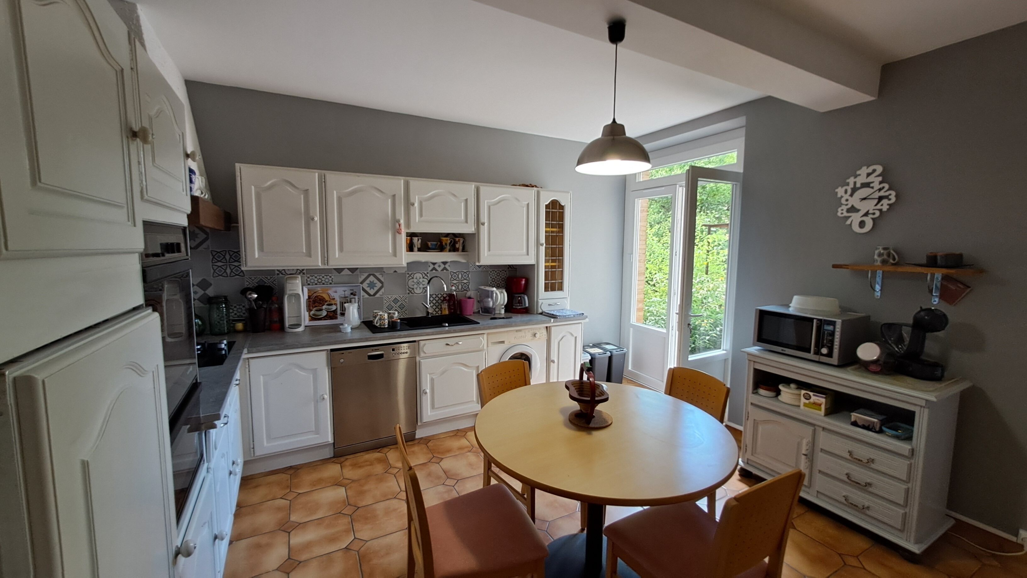 A kitchen with white cabinets, a dining table with chairs, a coffee maker, and a microwave.