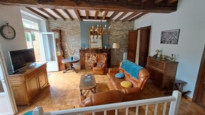 A living room with a leather sofa, wooden coffee table, and a television. There is a fireplace with a mirror above it, and a chandelier hanging from the ceiling. - The 3-star “Gîte de la Halle”   (Beaumont-de-Lomagne)