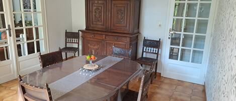 Un comedor con una mesa de madera, sillas, un aparador y un frutero.