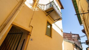 Eine enge Straße mit einer Gebäudeecke, einem sichtbaren Fenster und einer Tür mit der Hausnummer 78.