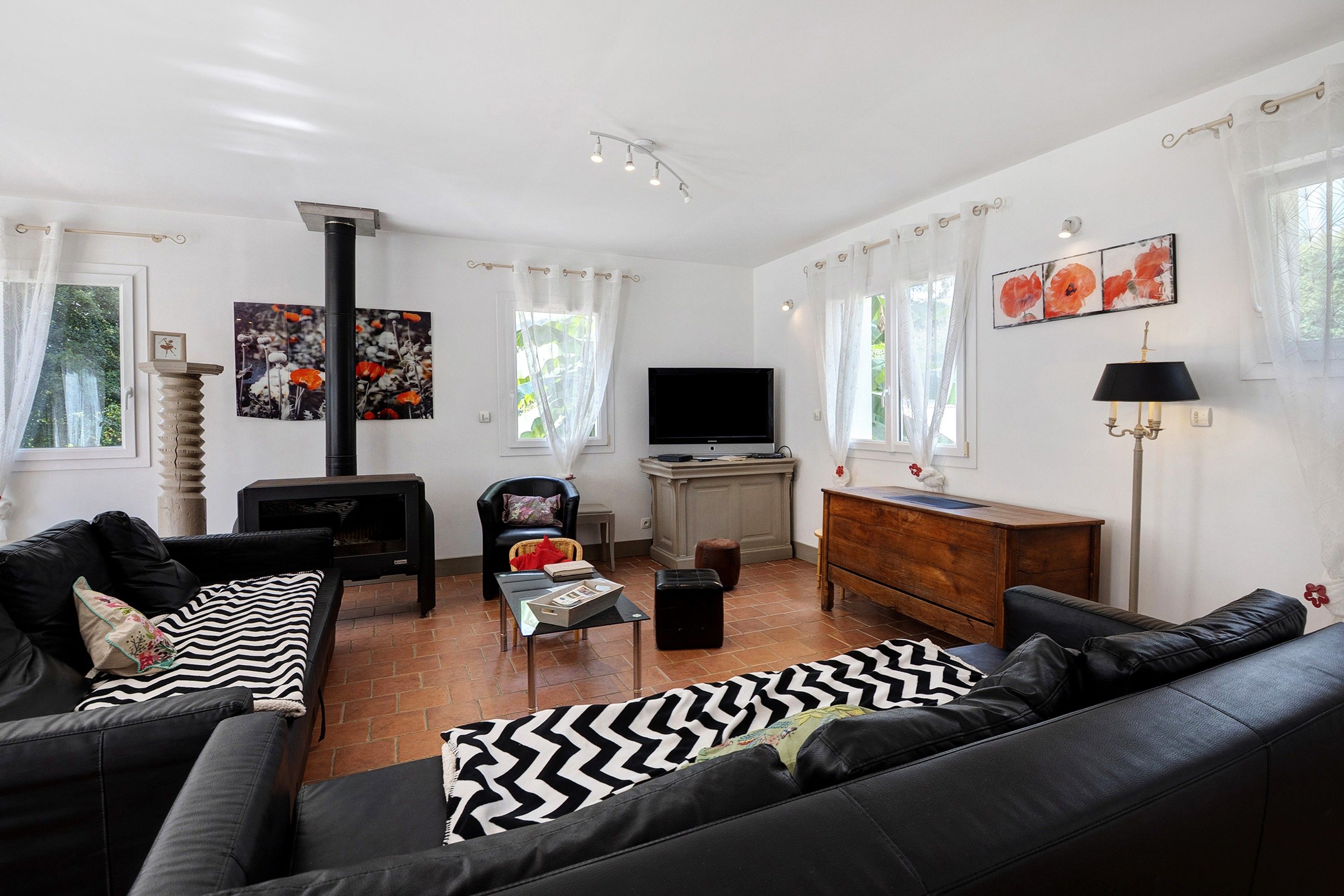 Ein Wohnzimmer mit einer schwarzen Couch, einem Fernseher, einem Kamin und Kunstwerken an den Wänden.