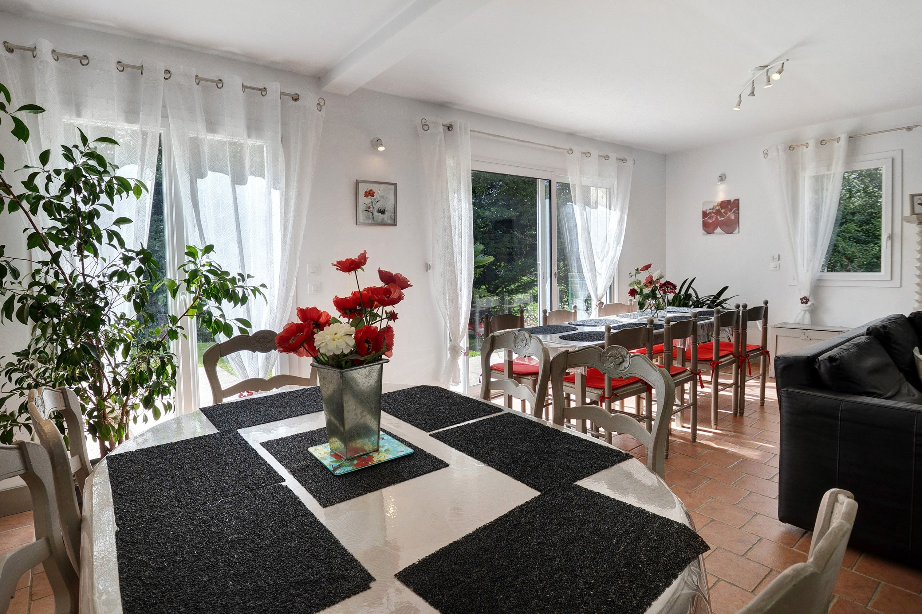 A dining area with a table set for four, surrounded by chairs, and a black and white checkered floor mat.