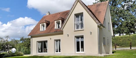 Une maison à deux étages, dotée d’un toit en pente, de grandes fenêtres et d’une pelouse bien entretenue.