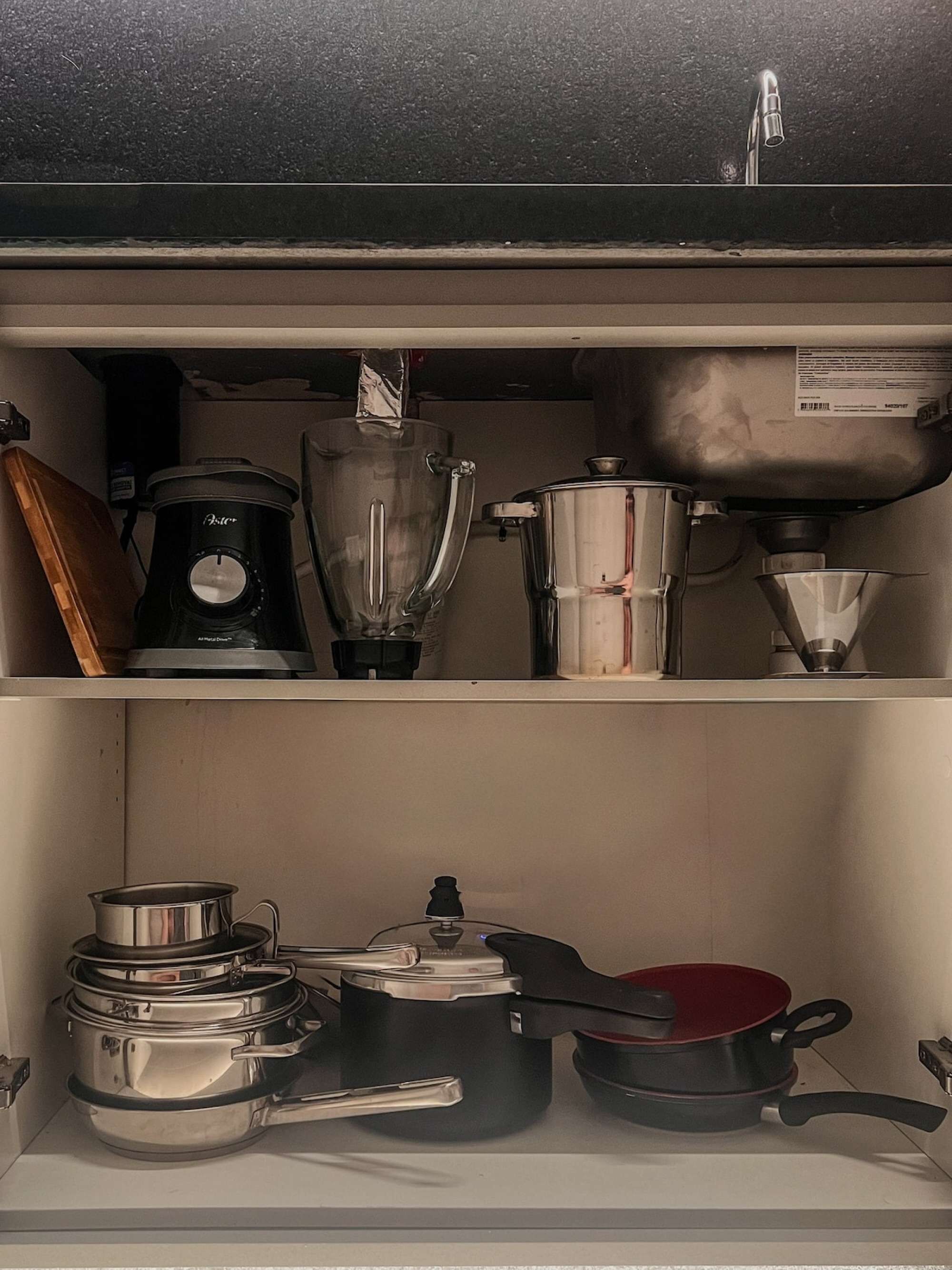 Una cocina con cafetera, licuadora, hervidor y ollas en los estantes.
