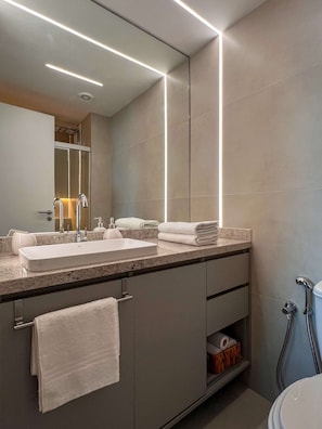 A modern bathroom with a large mirror, two sinks, a towel rack, and a shower area.