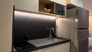 A modern kitchen with a built-in microwave, stainless steel refrigerator, and a black countertop. - Beachfront w/ an amazing rooftop - Prime location (Salvador)