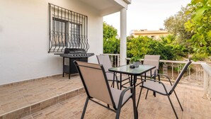 Eine Terrasse im Freien mit Grill, Tisch und Stühlen.