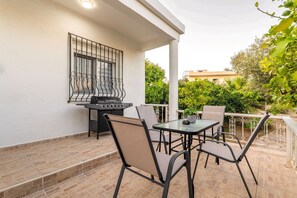 Eine Terrasse im Freien mit Grill, Tisch und Stühlen.
