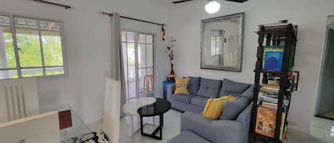 Una sala de estar con sofá, reposapiés y ventilador de techo.