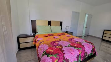 A bedroom with a bed, nightstands, a lamp, and a door.