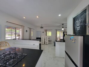 A modern kitchen with a gas stove, a refrigerator, and a dining area with a table and chairs. - Villa Tropical - Penthouse 10 (Sosúa)