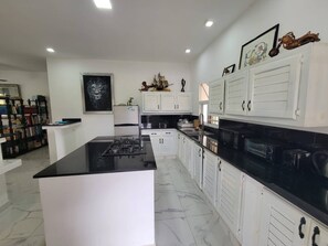 A modern kitchen with white cabinetry, a black countertop, and a marble floor. - Villa Tropical - Penthouse 10 (Sosúa)