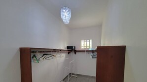 Ein Zimmer mit einem Holzschrank, einer Wäscheständer und einer Deckenleuchte.