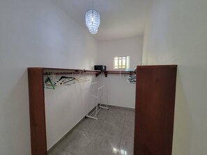 A room with a wooden wardrobe, a clothes drying rack, and a hanging light fixture. - Villa Tropical - Penthouse 10 (Sosúa)