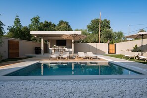 A pool area with lounge chairs, a barbecue grill, and a covered seating area. - Villa Idola Dassia Corfu (Dassia)
