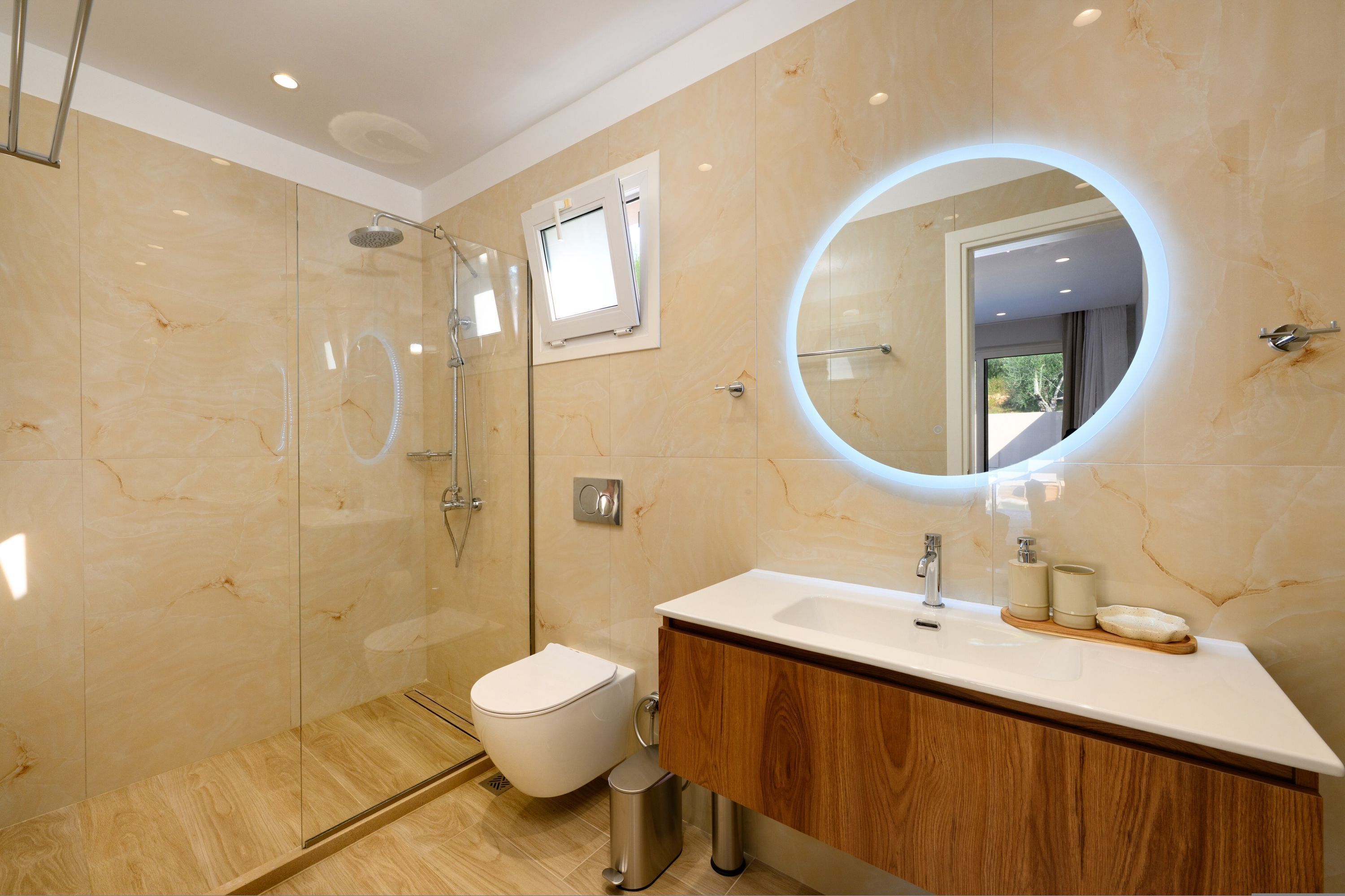 Een moderne badkamer met een douchecabine van glas, een toilet, een wastafelmeubel met spiegel en een wastafel.