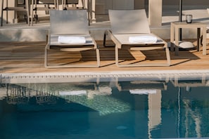 A poolside area with two lounge chairs and a table. - Villa Idola Dassia Corfu (Dassia)