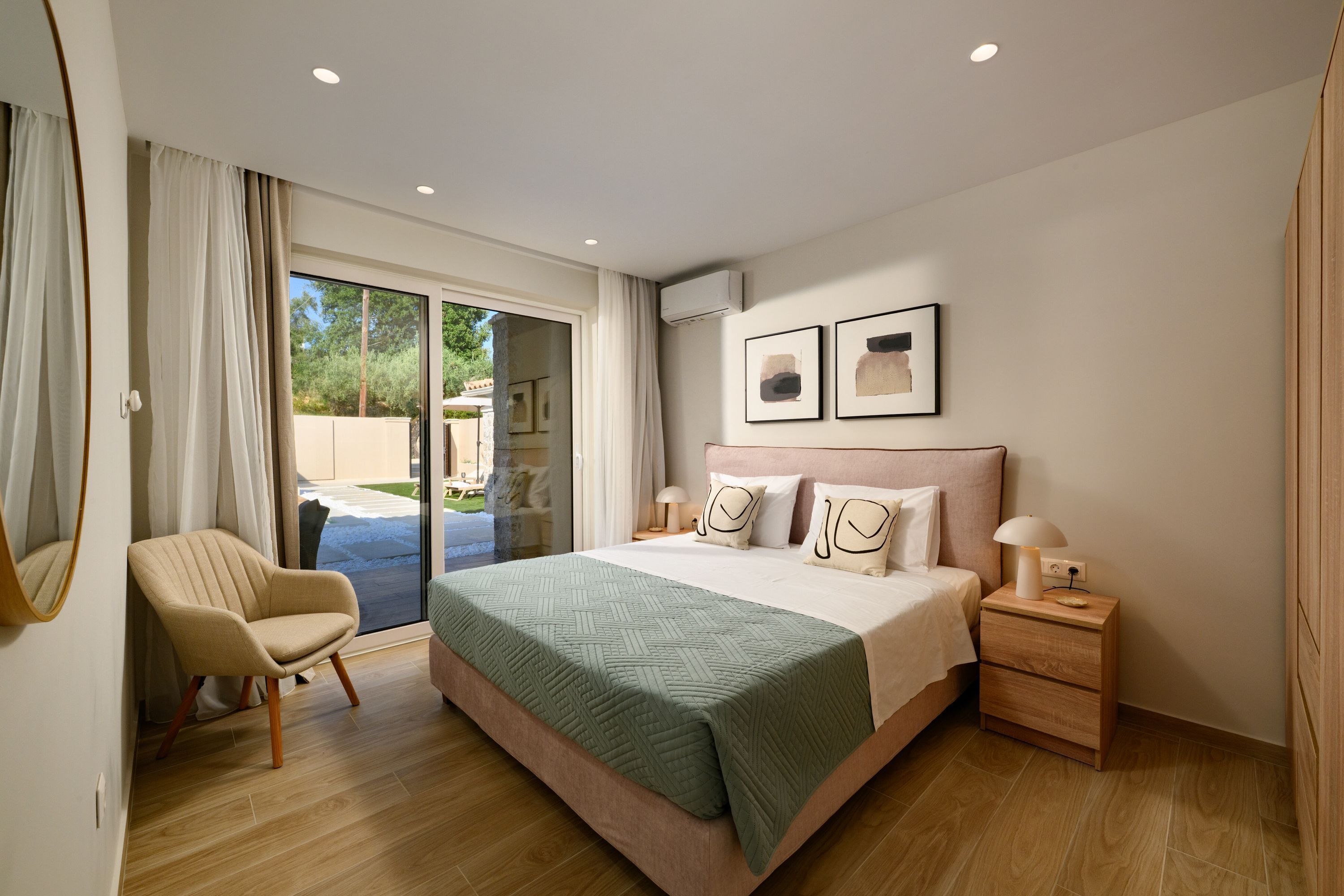 Une chambre à coucher avec un lit, une chaise, une table de chevet et une grande fenêtre.