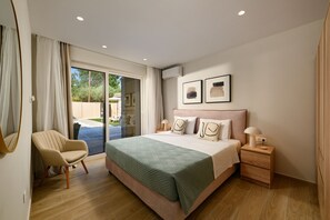A bedroom with a bed, a chair, a nightstand, and a large window. - Villa Idola Dassia Corfu (Dassia)