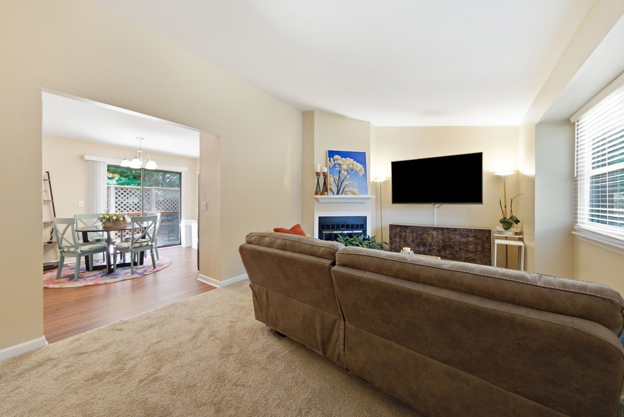 Una sala de estar con sofá, televisor de pantalla plana, chimenea y comedor con mesa y sillas.