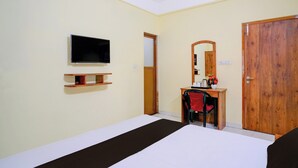 A hotel room with a bed, a desk, a television, a mirror, and a wardrobe. - Super Collection O Bashista Chariali (Guwahati)