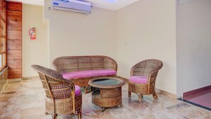 A room with a wicker sofa set, a small table, and a wall-mounted air conditioning unit. - Super Collection O Bashista Chariali (Guwahati)