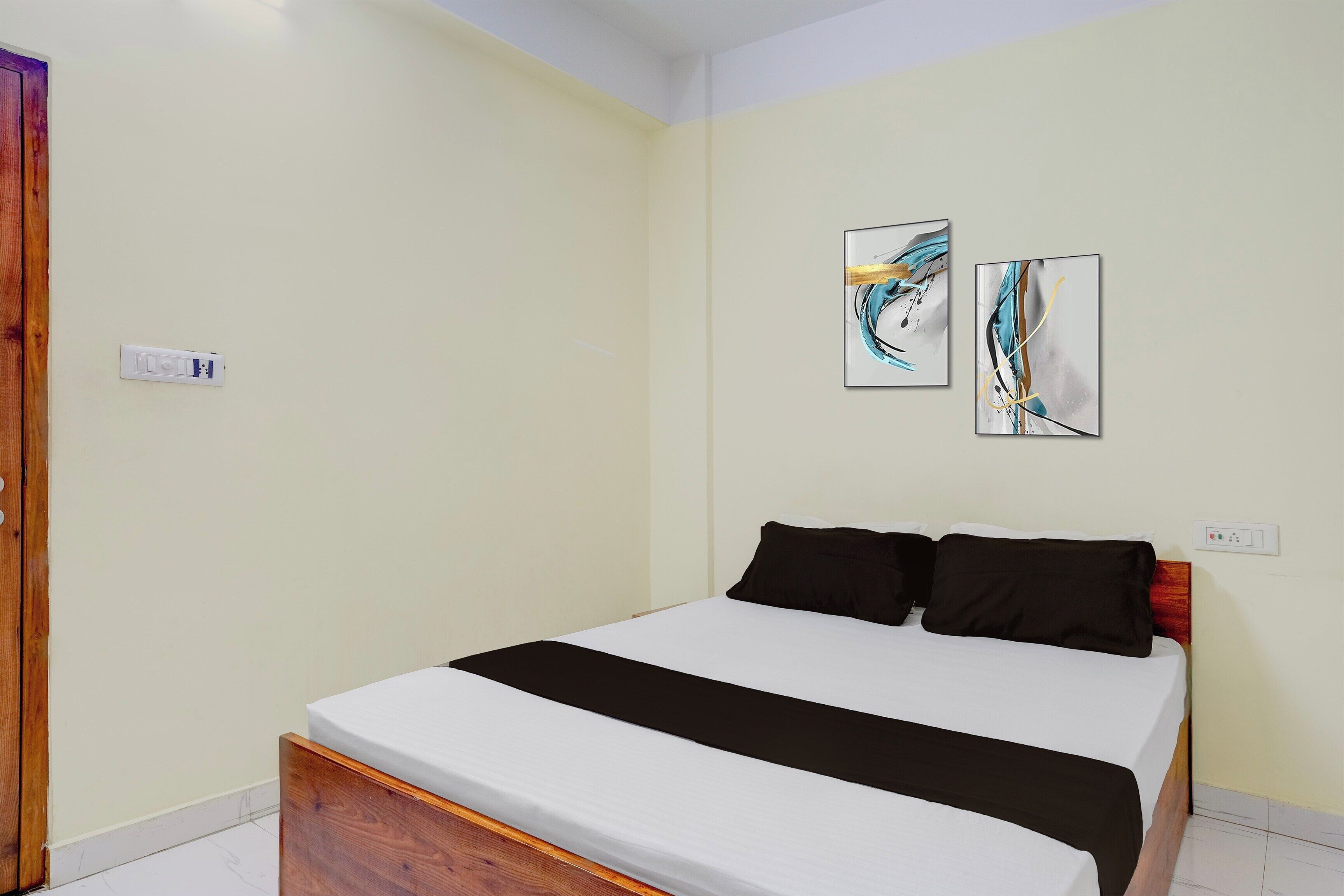 Un dormitorio con una cama, dos cuadros en la pared y un enchufe.