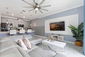 Ein modernes Wohnzimmer mit einer Couch, einem Couchtisch und einem Wand-Fernseher.