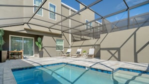 A swimming pool with a glass ceiling, lounge chairs, and a table with chairs. - Chic Home Just 15 Min to Disney (Davenport)