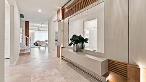 A modern hallway with a built-in bench, a potted plant, and a staircase leading to another room. - Orlando Most Incredible Themed 10br Villa (Clermont)