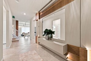 Ein moderner Flur mit integriertem Sitzplatz, einem Blumentopf und einer Treppe, die in einen anderen Raum führt.
