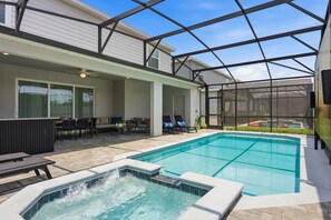 Ein Schwimmbecken mit Whirlpool, Sitzgelegenheiten im Freien und einer überdachten Terrasse.